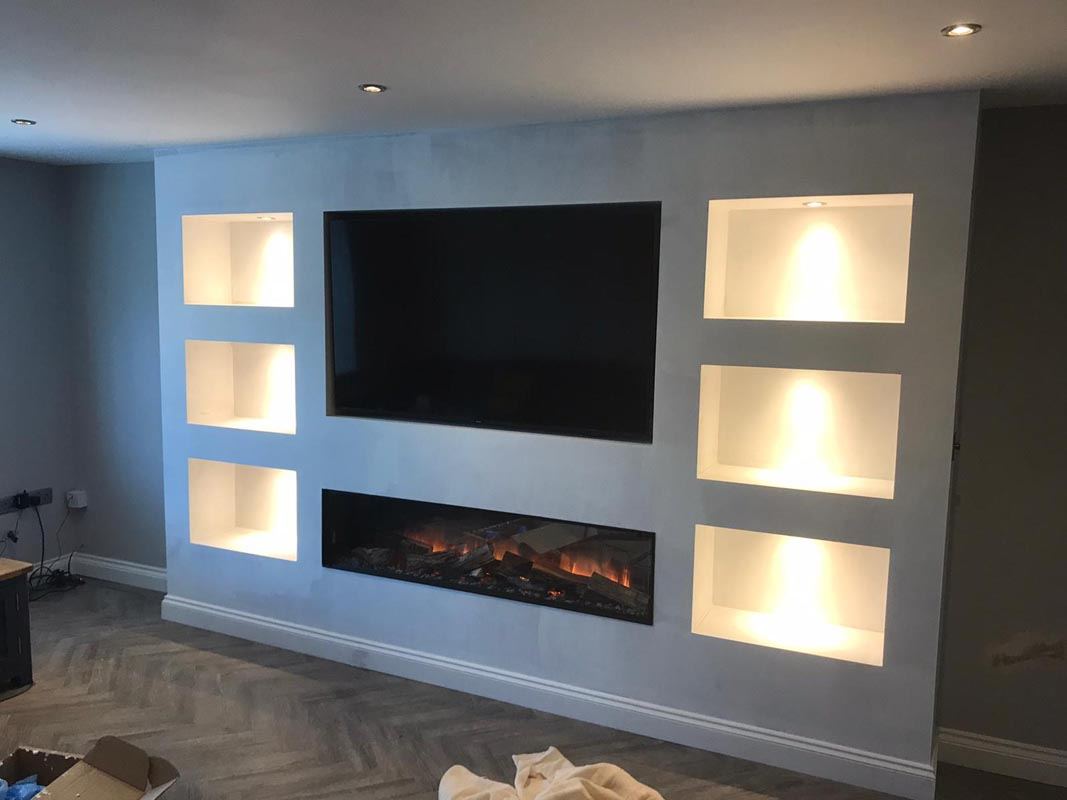 Custom bespoke media wall with integrated shelving and concealed lighting